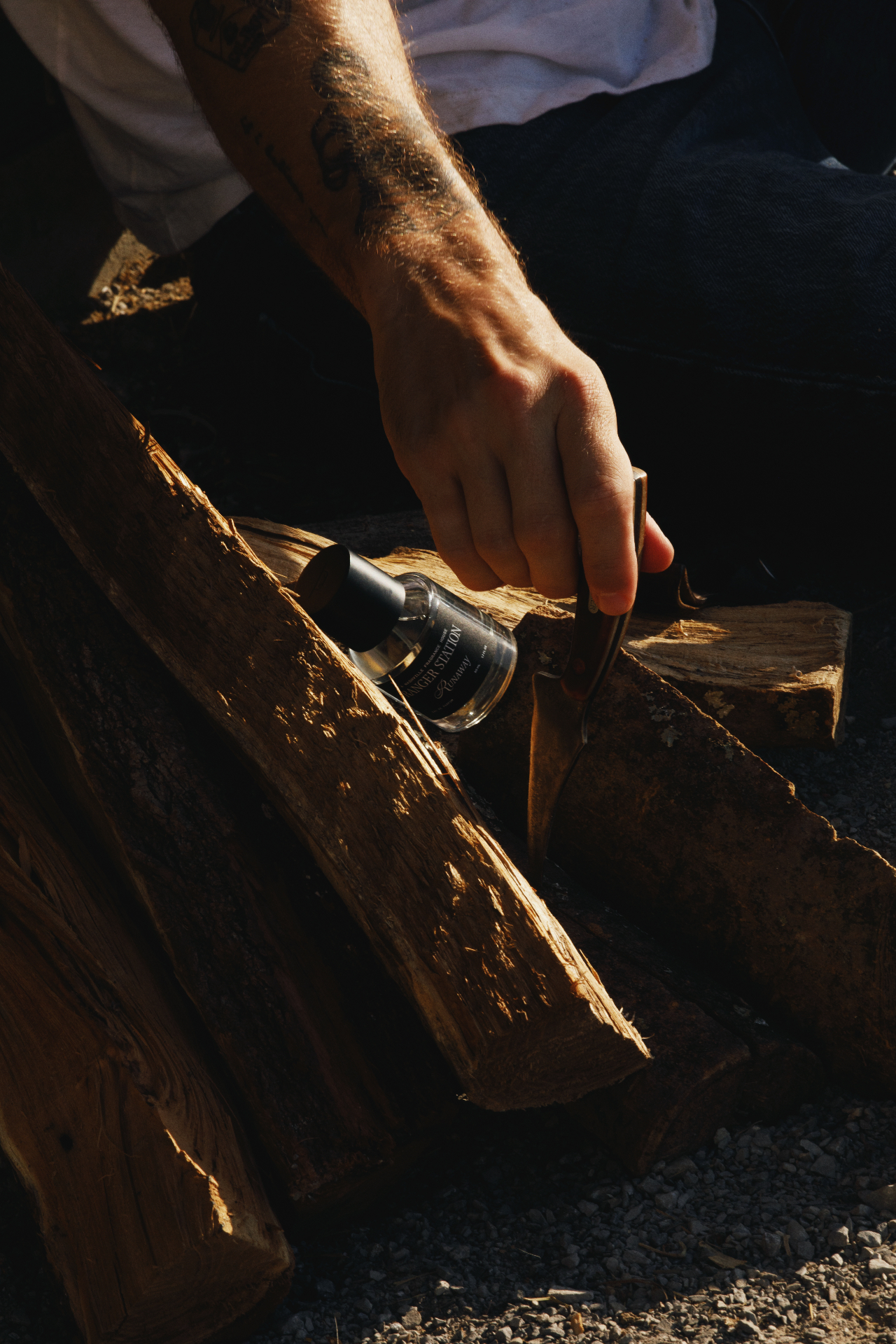 A hand reaching for a bottle of Runaway resting on split cedar wood